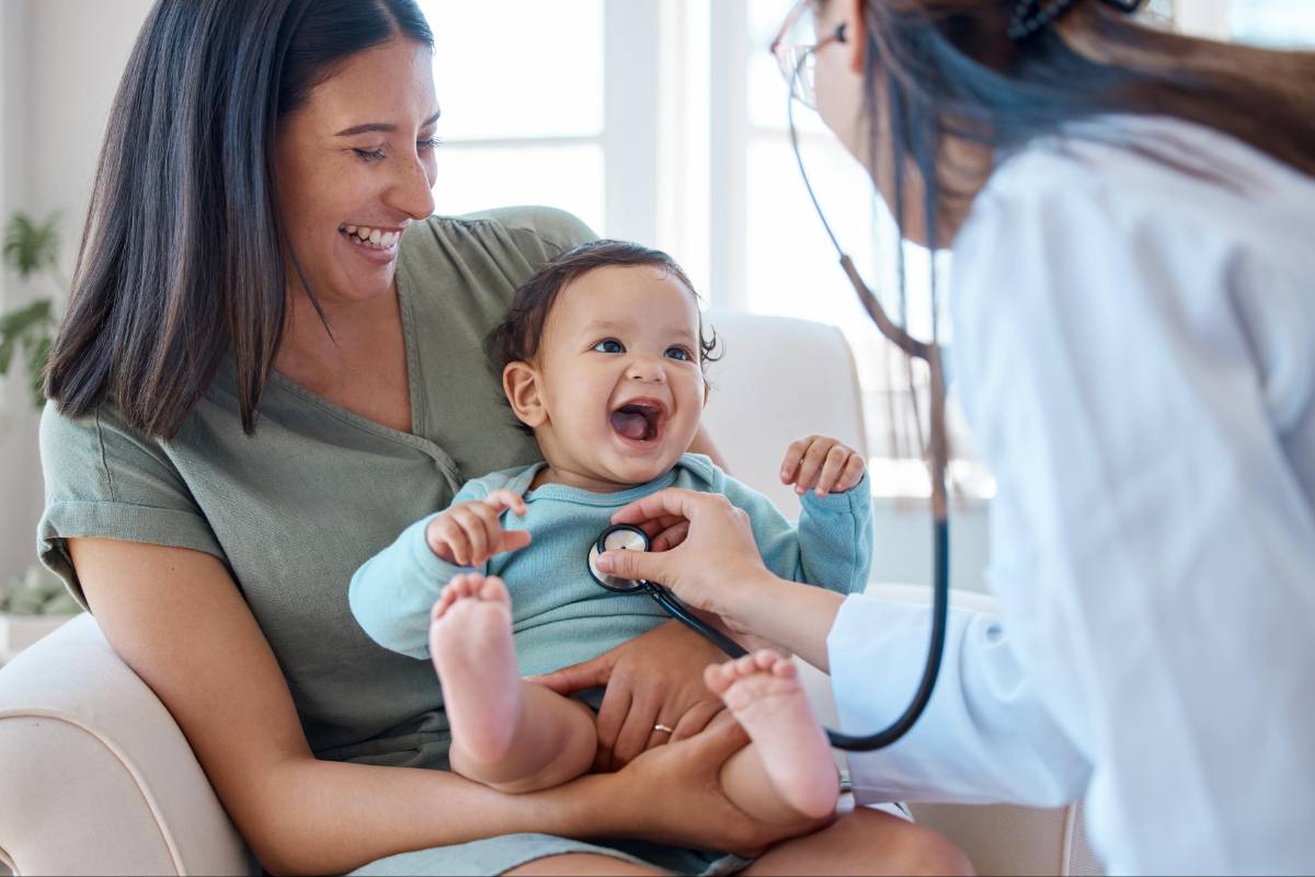 A woman holds her baby as a A woman holds her baby as a doctor examines the infant, illustrating compassionate primary care examines the infant, illustrating compassionate primary care